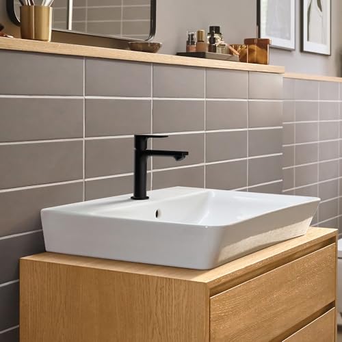 Chrome single-hole bathroom faucet with lever handle mounted on white rectangular vessel sink.