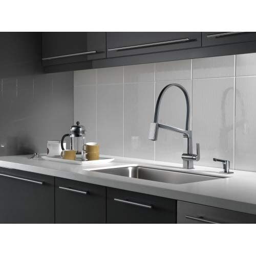Stainless steel soap and lotion dispenser with rectangular pump top mounted on white kitchen countertop.