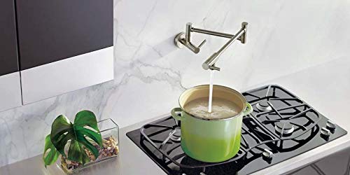 Moen black stainless steel wall-mount swing arm pot filler faucet above stovetop filling green pot with water.
