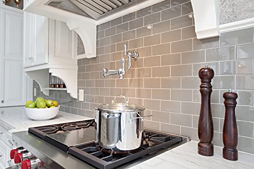 Unlacquered brass pot filler faucet mounted on kitchen backsplash above stovetop with pot.