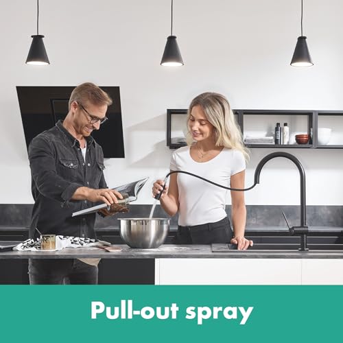 Matte black high-arc kitchen faucet with pull-down spray head installed at sink with two people cooking.