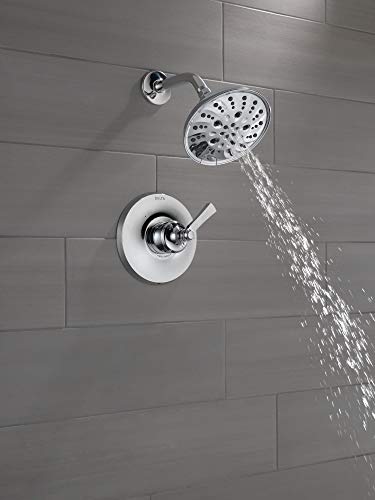 Chrome tub filler with single-handle valve and multi-function showerhead mounted on gray tile wall.