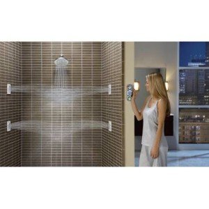 Chrome square rainshowerhead mounted on tiled shower wall with water stream visible, woman standing nearby.
