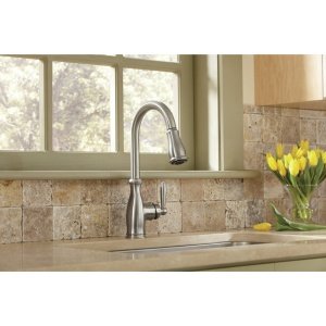 Oil rubbed bronze pull-down kitchen faucet with curved spout and side handle mounted above sink.