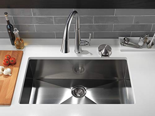 Chrome pull-down kitchen faucet with arched spout mounted above stainless steel sink.
