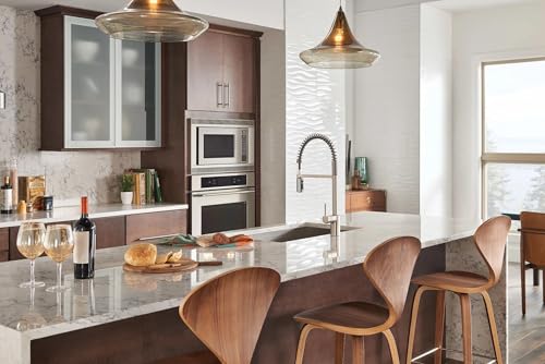 Stainless steel pull-down kitchen faucet with high arc spout mounted above white countertop sink.
