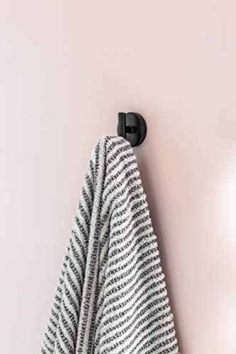 Polished nickel robe hook mounted on white wall with striped towel hanging from it.
