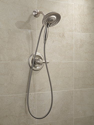 Stainless steel shower system with fixed head, handheld sprayer, and valve mounted on beige tile wall.