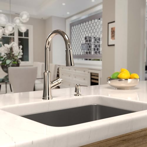 Polished nickel high-arc kitchen faucet with pull-down spray head installed in white countertop sink.