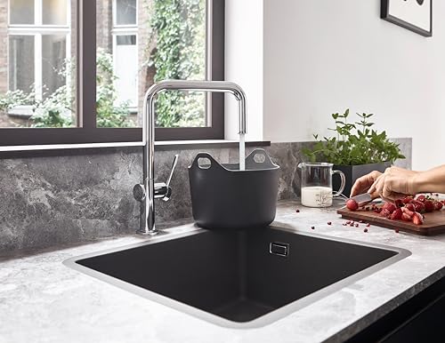 Chrome U-shaped kitchen faucet with single spray head mounted above black undermount sink.