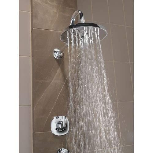 Stainless steel shower arm with round showerhead mounted on tiled bathroom wall, water flowing from nozzles.