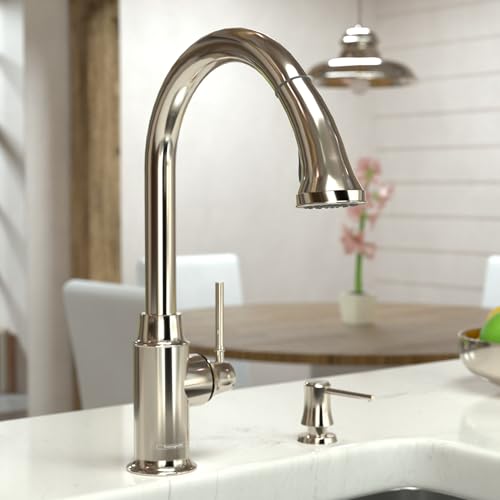 Polished nickel kitchen faucet with high arc spout and pull-down spray head mounted on white sink.
