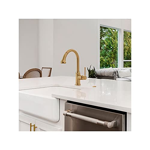 Brushed gold high-arc kitchen faucet with pull-down spray installed above a white apron-front sink.
