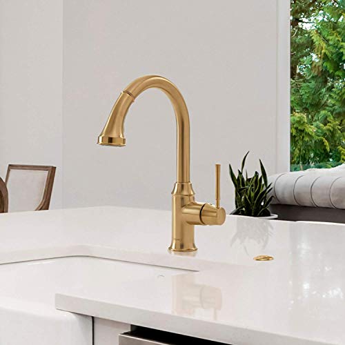 Brushed gold kitchen faucet with high arc spout and pull-down spray head mounted on white countertop sink.