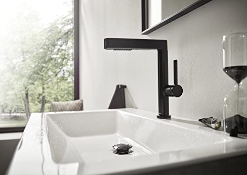 Matte black single-hole kitchen faucet with pull-out spray head installed above white sink.