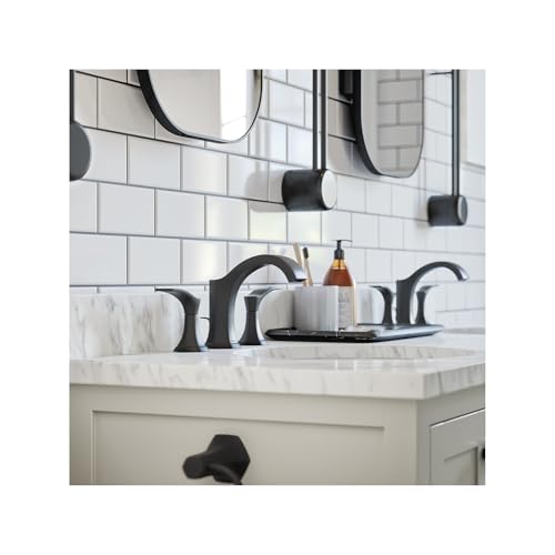 Matte black widespread bathroom faucet with curved handles and pop-up drain installed on marble countertop.