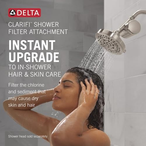 Stainless steel Delta Clarifi shower filter attachment with perforated spray face installed on shower arm.