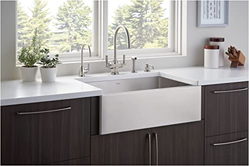 Satin English Gold soap dispenser with tall curved spout positioned on white kitchen countertop beside farmhouse sink.