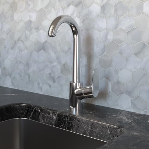 Chrome bar faucet with curved spout mounted on dark countertop against hexagonal tile backsplash.