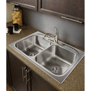 Stainless steel double-basin drop-in kitchen sink with single-handle faucet mounted on countertop.