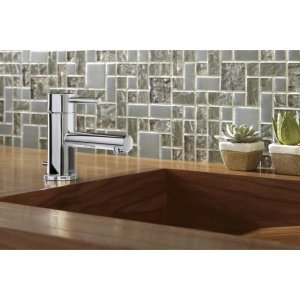 Matte black single-handle bathroom faucet with tall spout mounted on brown sink, with mosaic tile backsplash.