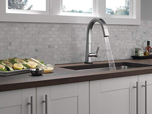 Chrome pull-down kitchen faucet with single handle mounted above dark countertop sink.