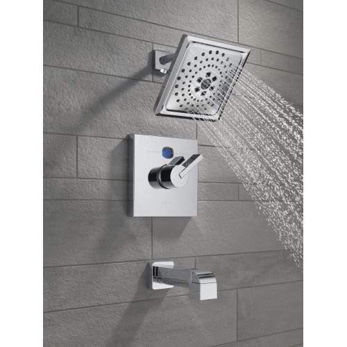 Polished nickel shower arm mounted on gray tile wall with square showerhead and water spray.