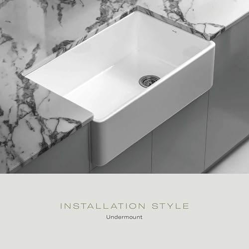 White fireclay undermount sink with single basin and drain, installed beneath marble countertop.