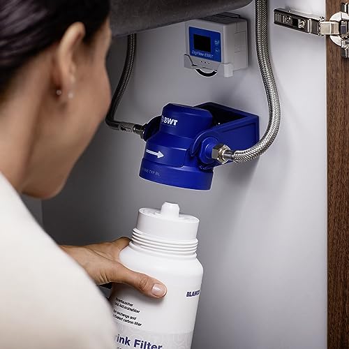 White cylindrical filter cartridge with threaded cap being held up to blue water filter unit mounted on wall.