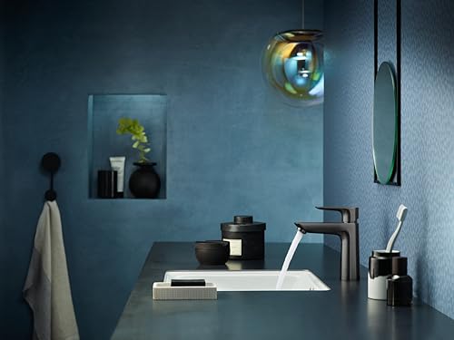 Black chrome single-hole faucet with curved spout and pop-up drain installed in bathroom sink.