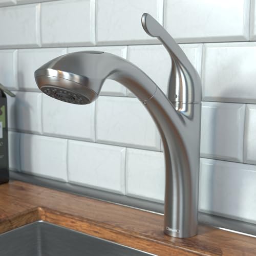 Steel optic kitchen faucet with curved spout and pull-out spray head mounted above wooden countertop and white tile backsplas