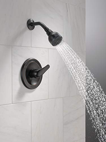 Oil rubbed bronze shower trim kit with single lever handle and overhead showerhead mounted on white tile wall.