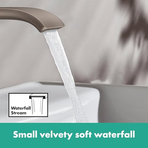 Brushed nickel single-hole bathroom faucet with curved spout dispensing water in a waterfall stream.