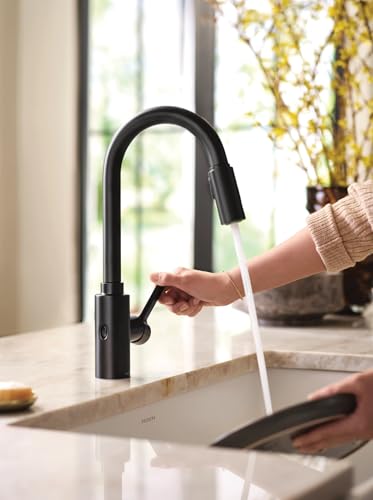 Matte black high arc kitchen faucet with pulldown spray head and touchless wave sensor, installed on countertop with water ru