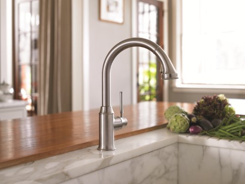 Stainless steel high-arc kitchen faucet with pull-down spray head mounted on marble countertop.
