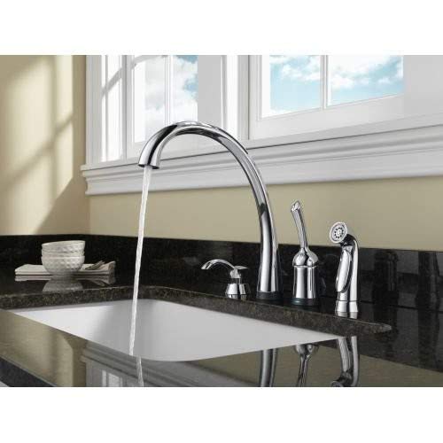 Polished stainless steel soap dispenser with tall curved spout mounted on black countertop beside kitchen faucet.