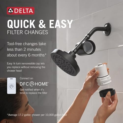Matte black Delta shower filter head mounted on tile wall with removable filter cartridge shown in hand below.