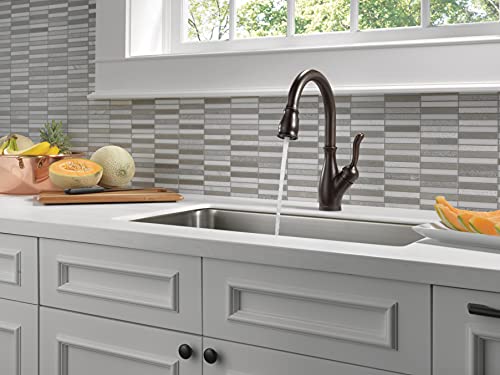 Black single-handle pull-down kitchen faucet with curved spout mounted above white undermount sink with gray and white tile b