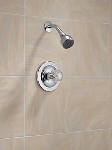 Chrome shower valve with round trim plate and matching showerhead mounted on beige tile wall.