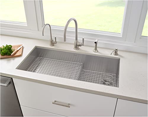 Satin English Gold soap dispenser mounted on white countertop next to stainless steel kitchen sink with faucet.