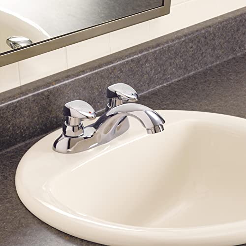 Chrome two-handle bathroom faucet with metering controls installed on white round sink.