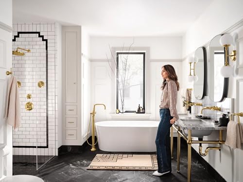 Brushed gold single-handle valve trim kit mounted on bathroom shower wall with white subway tiles and black grout.