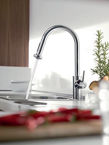 Polished nickel high-arc kitchen faucet with pull-down spray head extended over sink.