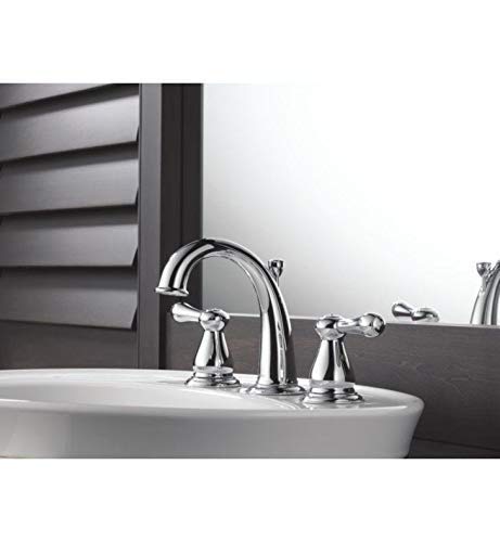 Polished stainless steel two-handle bathroom faucet with curved spout and lever handles installed on white sink.