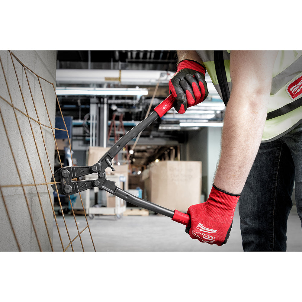 Person wearing red and black gloves holding an 18-inch bolt cutter with red and black handle near a wire fence.