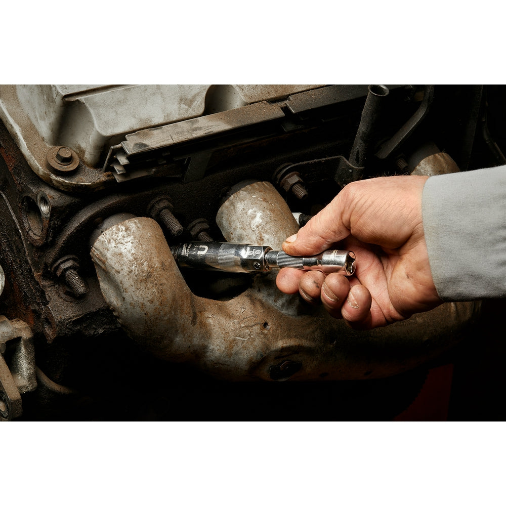 Magnetic spark plug socket held in hand positioned over engine spark plugs.
