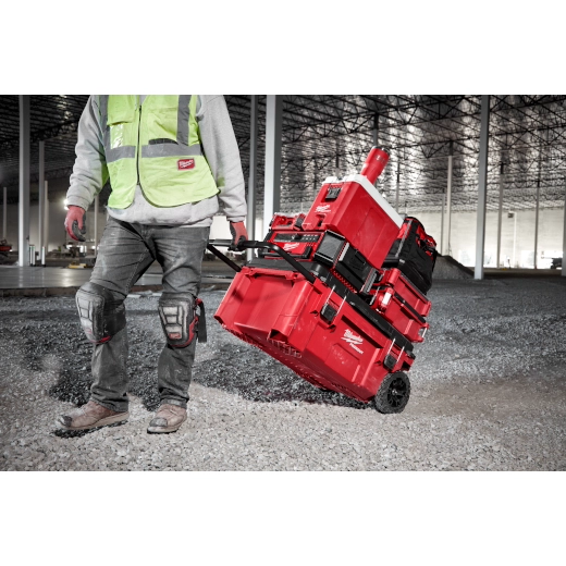 Red insulated tumbler with handle displayed on red modular storage cart in industrial warehouse setting.