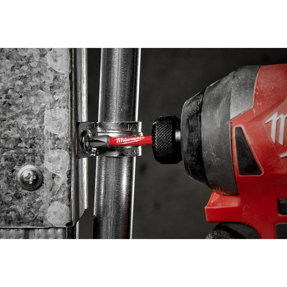 Milwaukee Shockwave Phillips #3 impact power bit inserted in red drill driver, driving screw into metal surface.