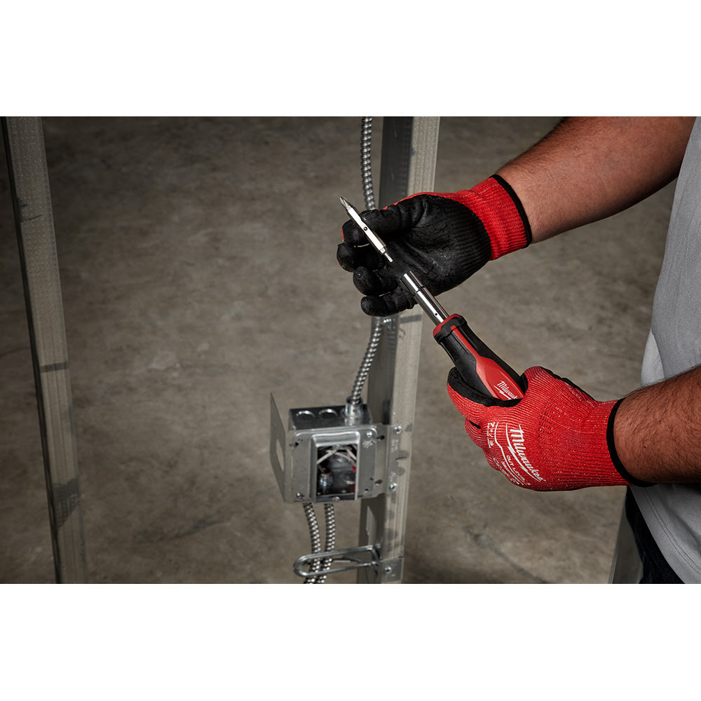 Milwaukee multi-bit screwdriver with red and black handle held in gloved hands during installation work.