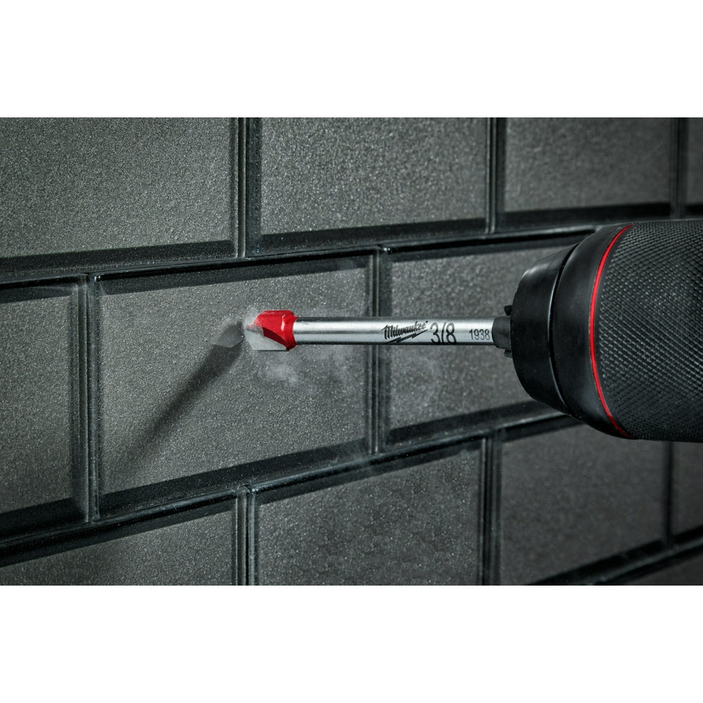 Milwaukee 5/16 inch carbide drill bit with red tip inserted in black brick surface.